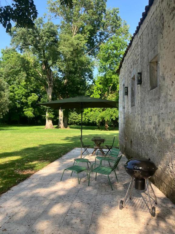 a grill and two chairs and a table with an umbrella at Beautiful riverside boathouse in Bourg-Charente