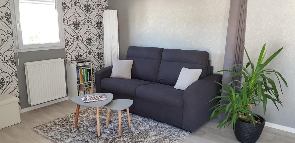 un salon avec un canapé bleu et une table dans l'établissement Au jardin de la seiche, à Noyal-Châtillon-sur-Seich