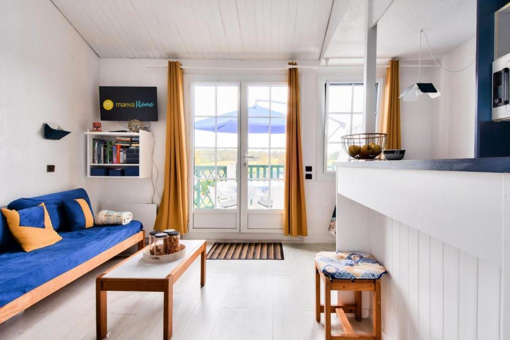 un salon avec un canapé bleu et une fenêtre dans l'établissement Résidence Port Bourgenay - maeva Home - Appartement 2 pièces 5 personnes - Sélection MAE-6174, à Talmont-Saint-Hilaire