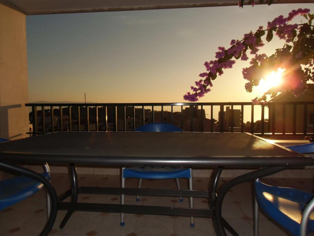 a table and chairs on a balcony with the sunset at Apartments Mustapic in Makarska