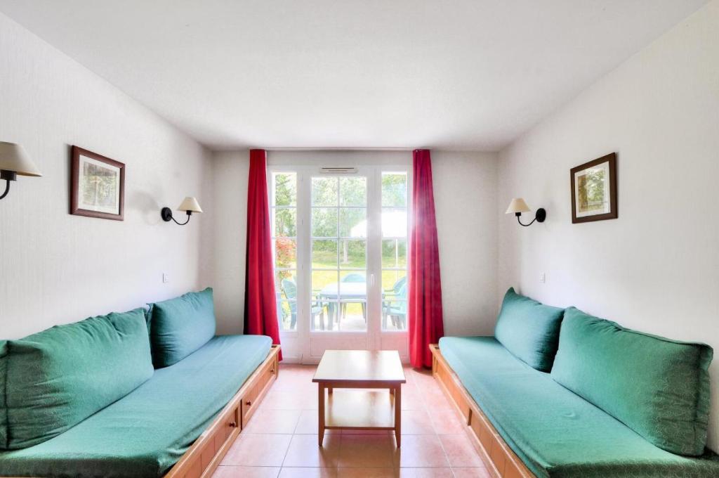 - un salon avec des canapés verts et une table dans l'établissement La résidence du Lac - maeva Home - Appartement 2 pièces 5 personnes - Sél 674, à Monflanquin