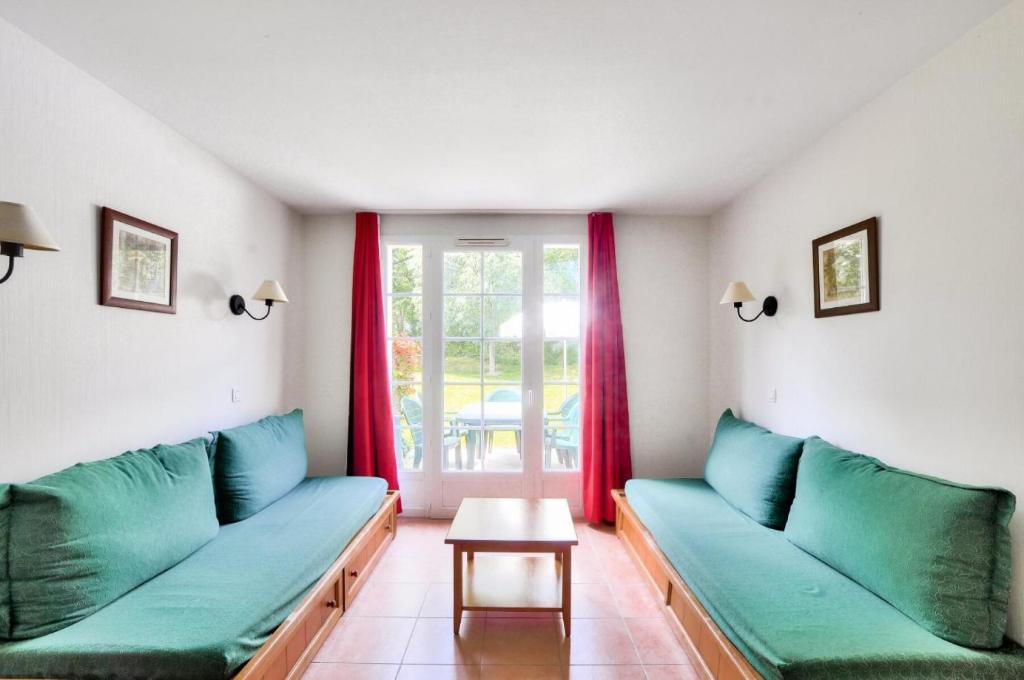 un salon avec des canapés verts et une table dans l'établissement La résidence du Lac - maeva Home - Appartement 2 pièces 5 personnes - Sélection MAE-3674, à Monflanquin