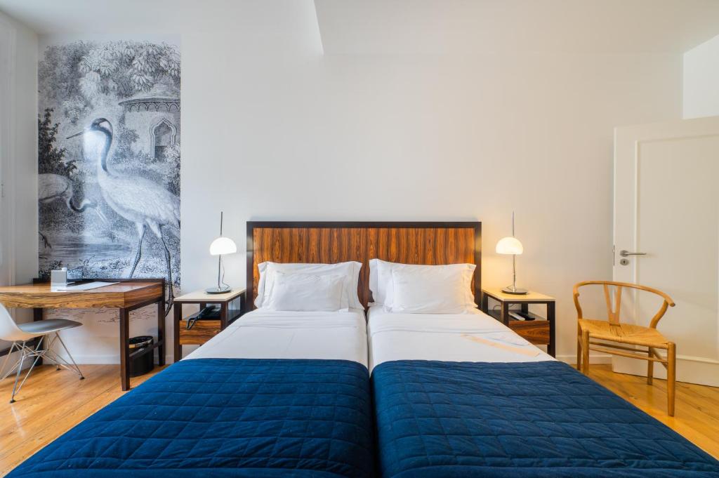 een slaapkamer met een groot bed en een blauwe deken bij Lisboa Prata Boutique Hotel in Lissabon