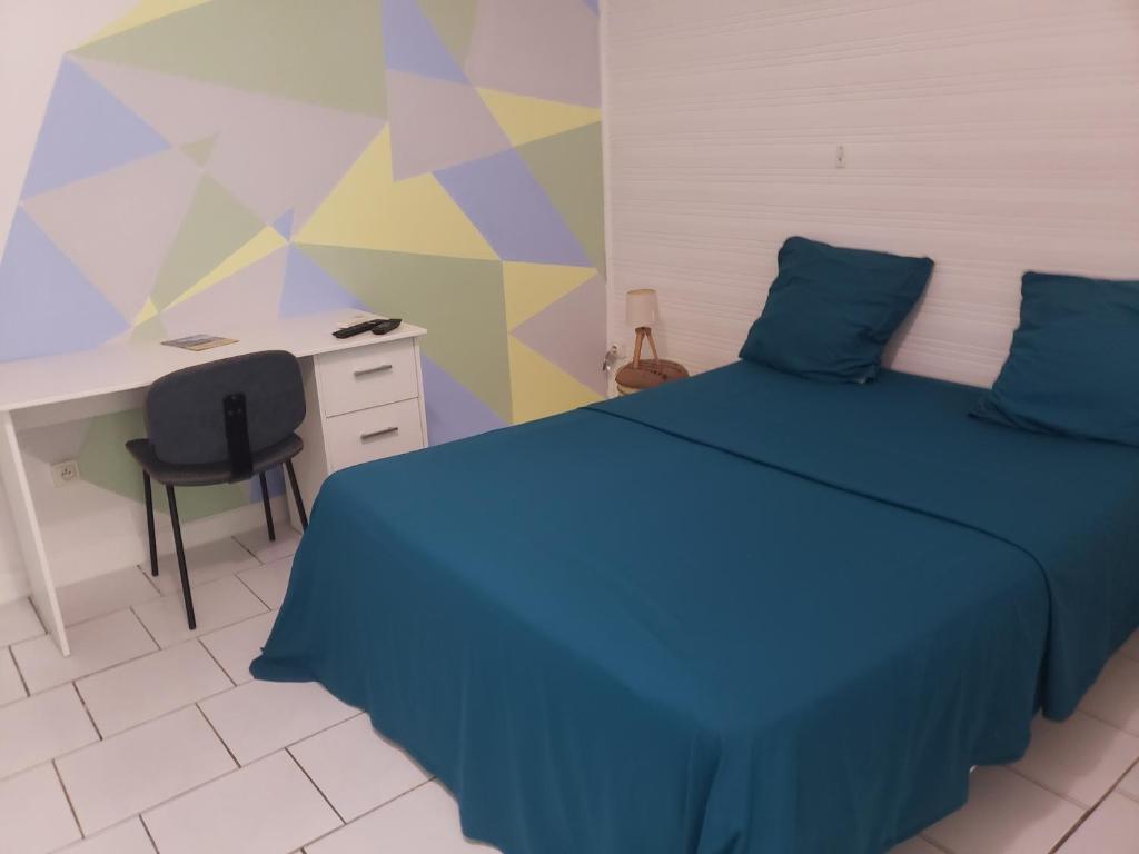 1 dormitorio con cama azul, escritorio y ordenador en ptit coin hibiscus en Pointe-Noire