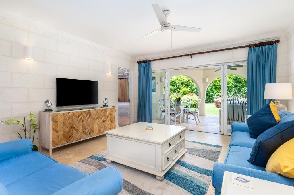 a living room with two blue couches and a tv at Royal Westmoreland - Royal Apartment 214 by Island Villas in Saint James