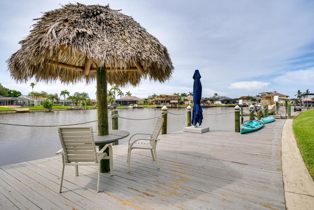 um pátio com uma mesa e cadeiras e um guarda-sol de palha em Cape Coral Home with Pool, Dock and Gulf Access! em Cape Coral