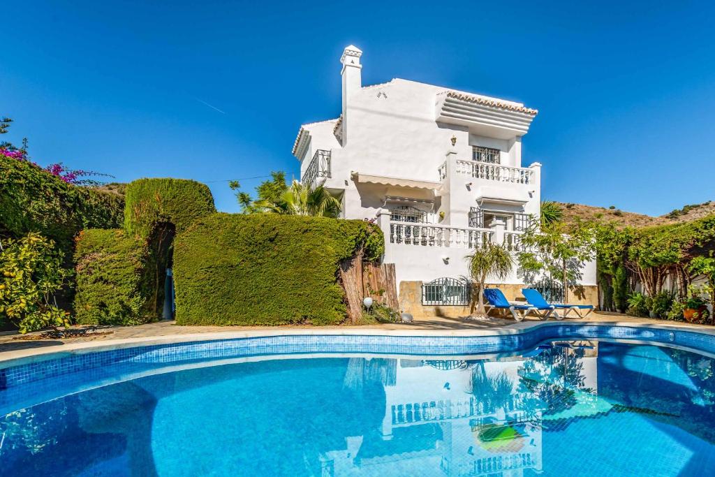 a large swimming pool in front of a white house at Casa Los Olivos in Nerja