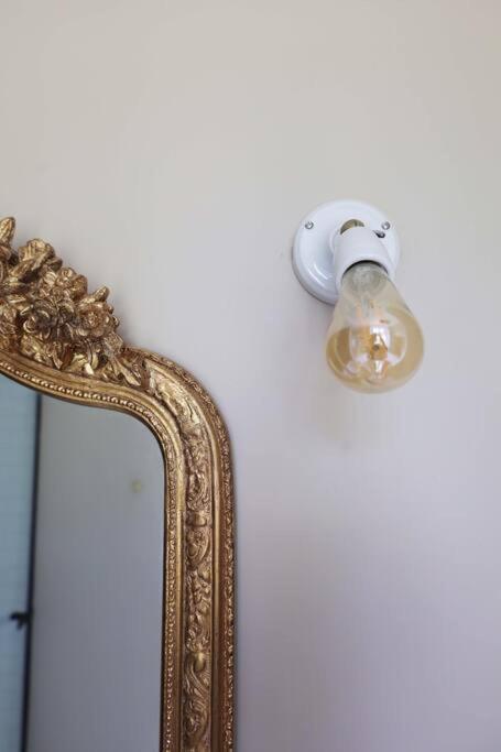 a mirror with a light attached to a wall at Le Perchoir Gîte de charme dans château in Brix