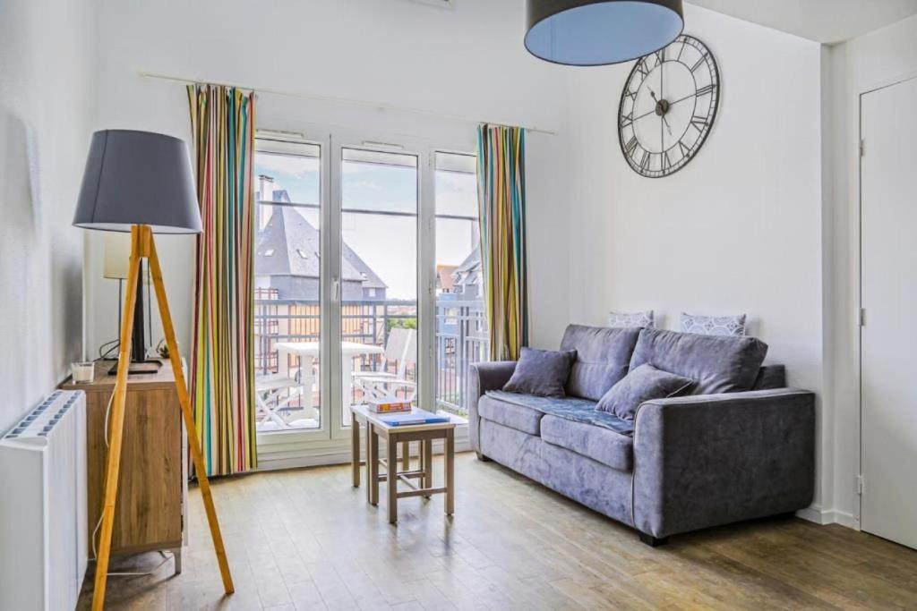 a living room with a couch and a clock on the wall at Résidence Port Guillaume - maeva Home - 3 Pièces 6 Personnes Sélection MAE-2368 in Dives-sur-Mer