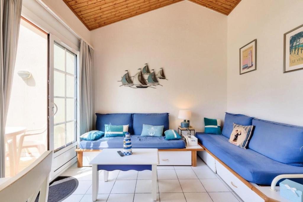un salon avec des canapés bleus et une table dans l'établissement Résidence Port Bourgenay - maeva Home - Appartement 3 pièces 6 personnes - Sélection MAE-9084, à Talmont-Saint-Hilaire