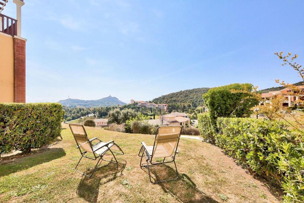 deux chaises assises sur l'herbe dans une cour dans l'établissement Résidence le Village de Cap Esterel - maeva Home - Appartement 2 pièces 4 personnes - Prestige MAE-2644, à Saint-Raphaël