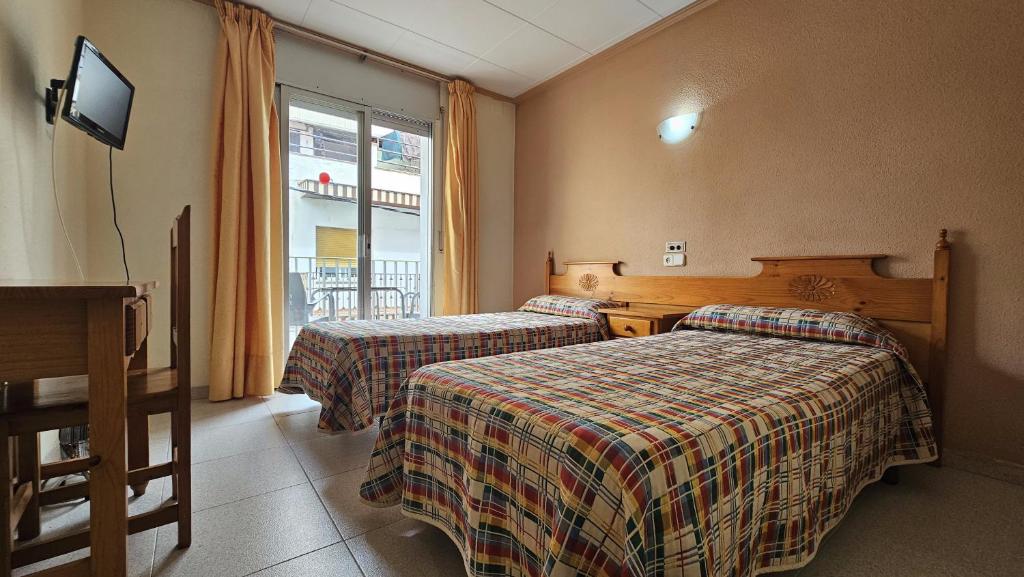 a hotel room with two beds and a window at Hostal Los Maños in Blanes