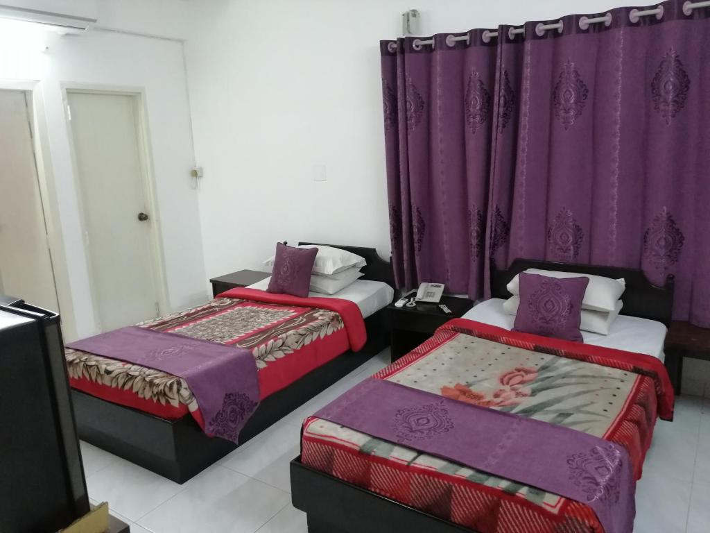 two beds in a room with purple curtains at Bay Marina Cox's Bazar in Kelātali