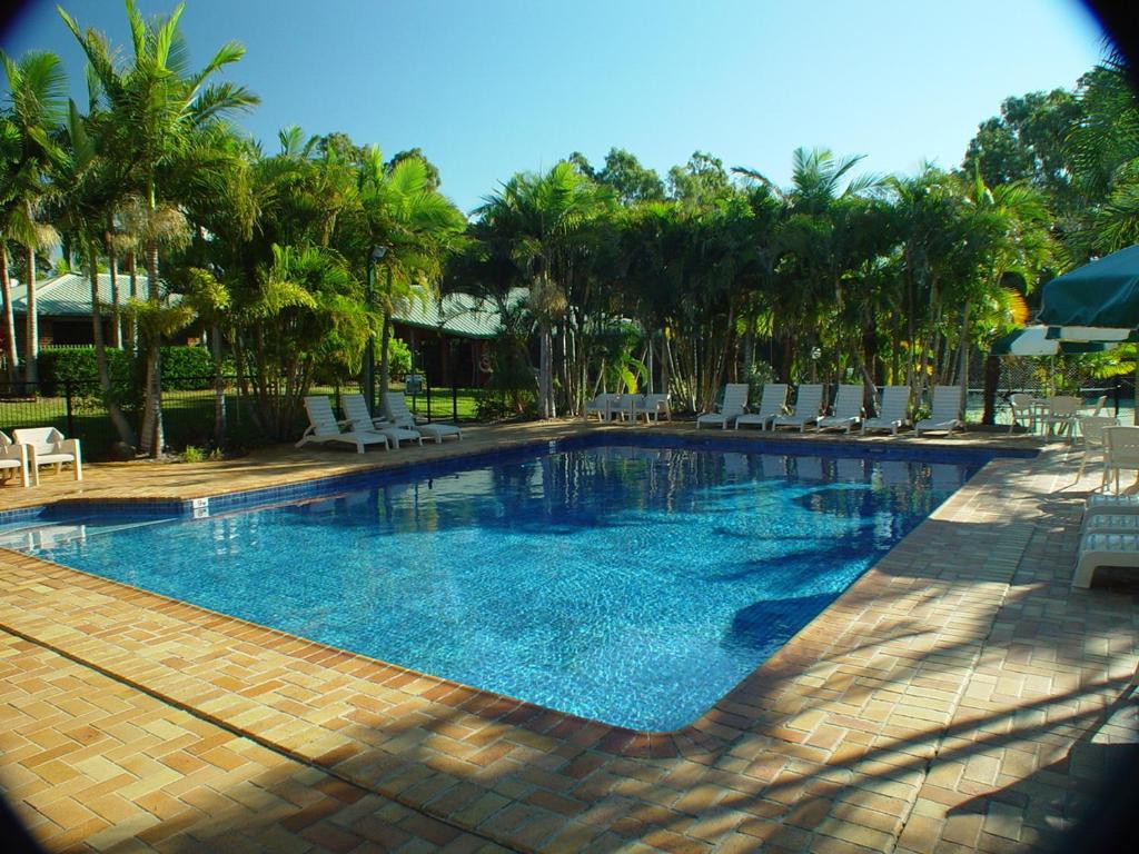 a large swimming pool with chairs and palm trees at Brisbane Gateway Resort in Rochedale