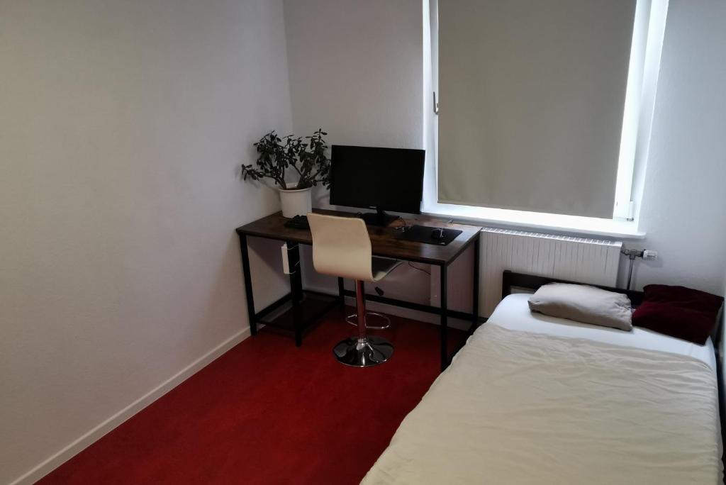 Kleines Zimmer mit einem Schreibtisch und einem Bett. in der Unterkunft Private Apartment in Hannover