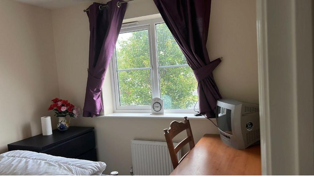 1 dormitorio con una ventana con cortinas moradas en Salimi en Bridgend