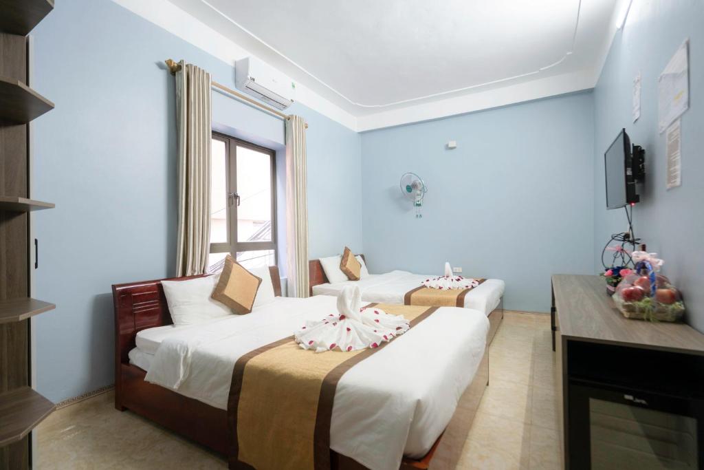 two beds in a room with a tv and a room with two beds at Fancy Hostel and Bar in Ha Long