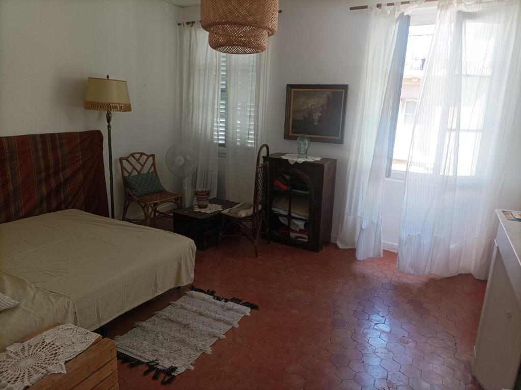 um quarto com uma cama, uma cadeira e uma janela em Jolie chambre dans appartement cosy en plein centre em Marselha