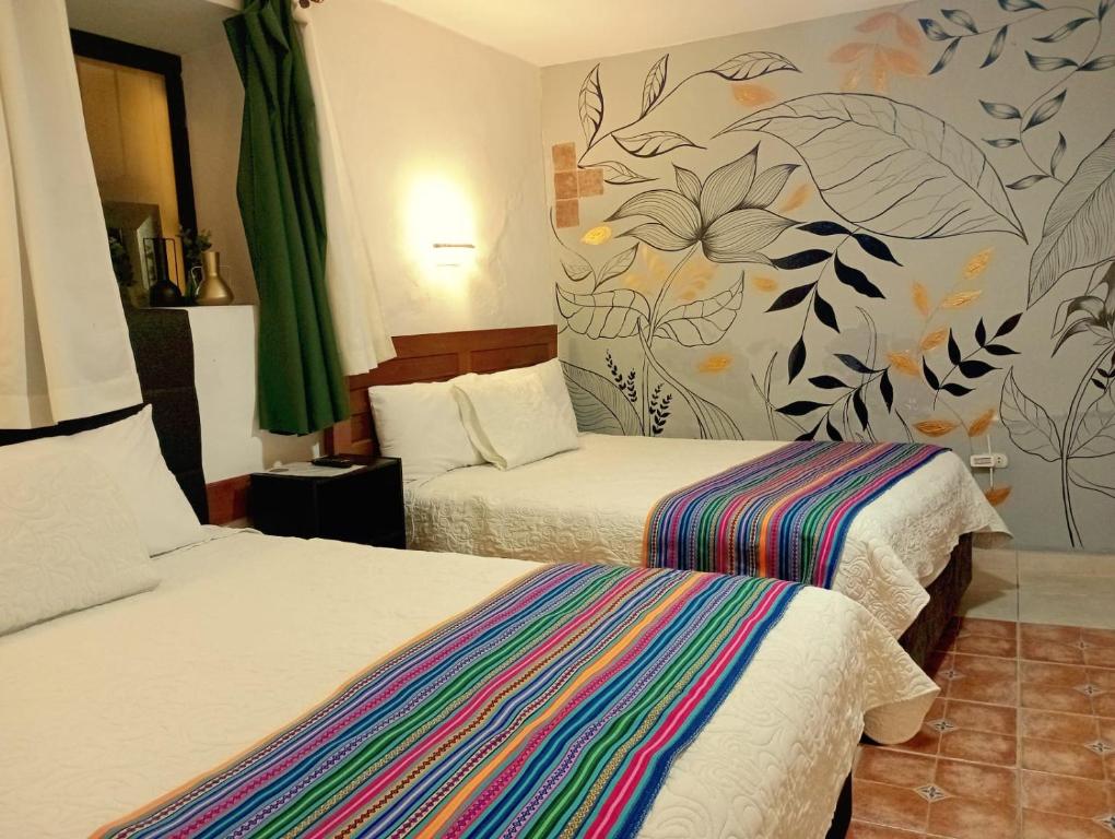 a hotel room with two beds and a mural on the wall at Hatuchay Inka Apart Hotel in Cajamarca
