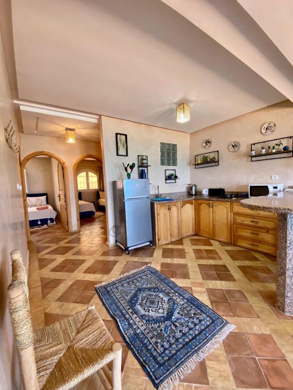 a large kitchen with a refrigerator and a table at Dar diafa samira in Mirleft