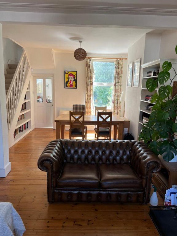un sofá de cuero en una sala de estar con mesa en Peaceful London Retreat, en Londres