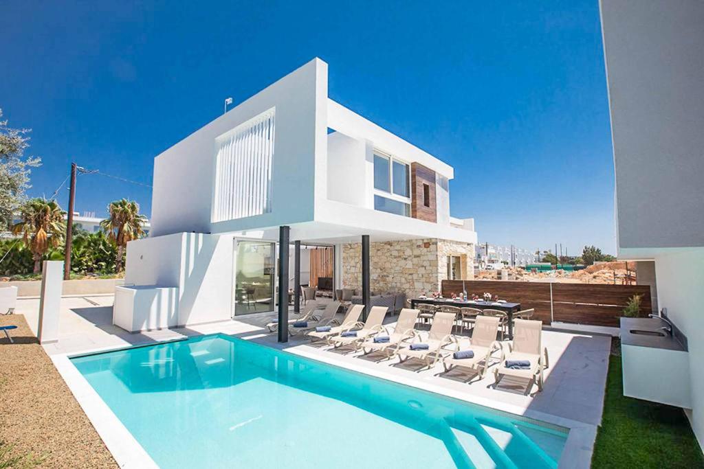 een wit huis met een zwembad en stoelen bij Nissi Cube 4 KB4 in Ayia Napa