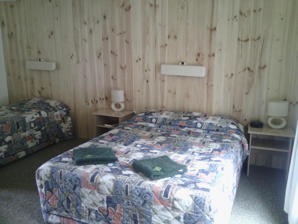a bedroom with a bed and two night stands and two tables at Snowy River Lodge Motel in Orbost