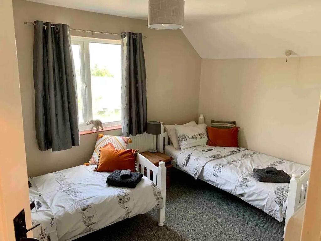 a bedroom with two beds and a window at Shipmeadow Cosy Cottage in Beccles