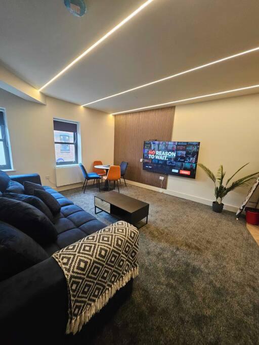 a living room with a couch and a flat screen tv at Stunning City Center Prime Location Flat - TV in every bedroom in Neath