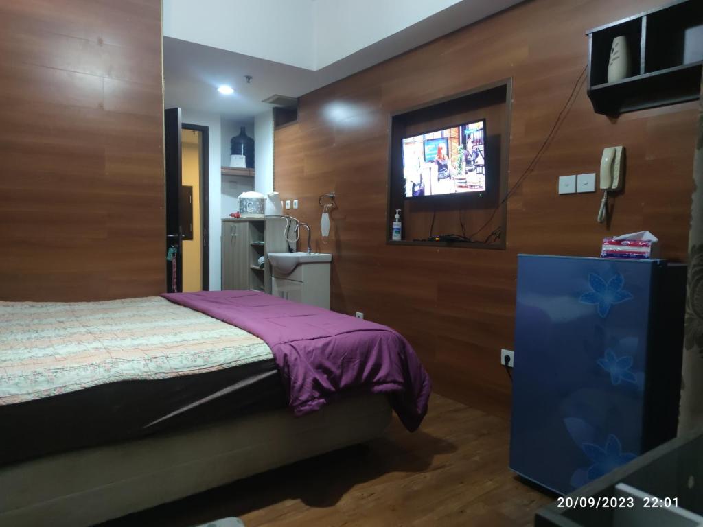 1 dormitorio con 1 cama y TV en la pared en APARTEMEN GRAND DHIKA 2325 BEKASI TIMUR, en Padurenan