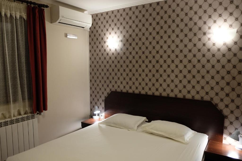 a bedroom with a white bed and a wall at Hotel Romantic in Sofia
