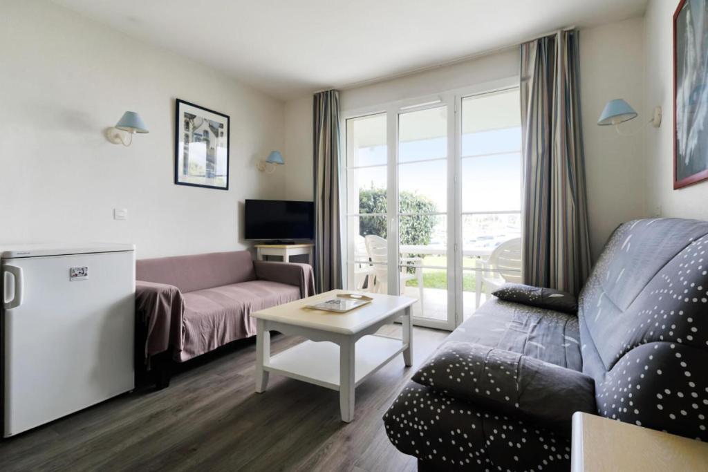 un salon avec un canapé et une table dans l'établissement Port du Crouesty Cap'Océan - maeva Home - 2 pièces 4 personnes - Sélection - vue sur le Port MAE-1693, à Arzon