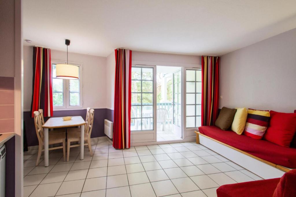 un salon avec un canapé rouge et une table dans l'établissement Village Moliets - maeva Home - 2 pièces 5 pers Sélection MAE-4493, à Moliets-et-Maa