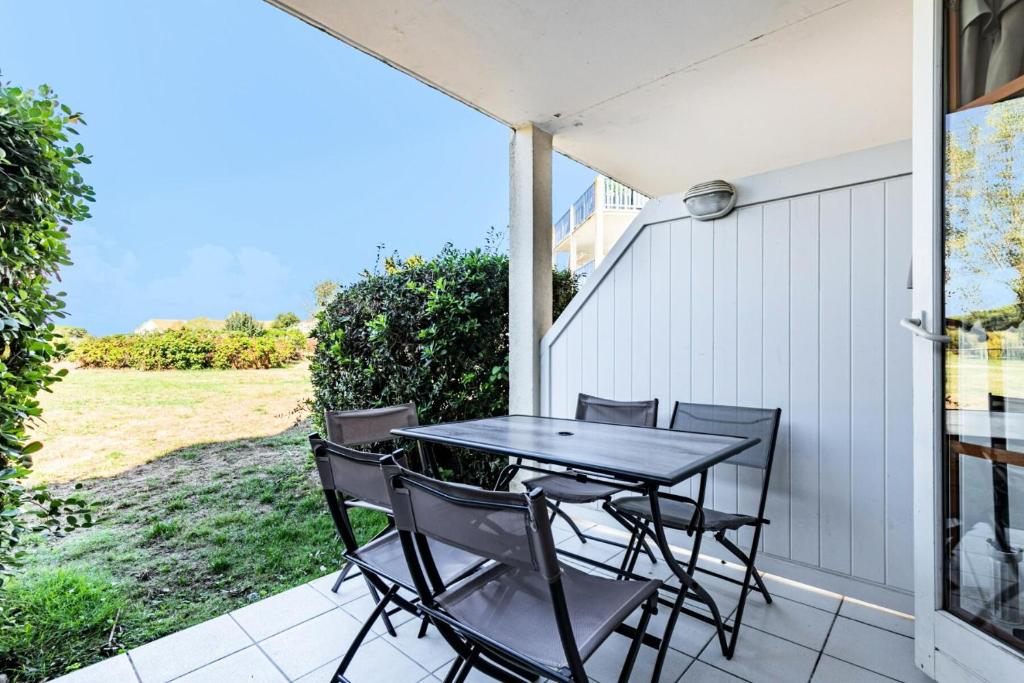 une terrasse couverte avec une table et des chaises. dans l'établissement Résidence Port Bourgenay - maeva Home - Appartement 2 pièces 5 personnes - 39, à Talmont-Saint-Hilaire