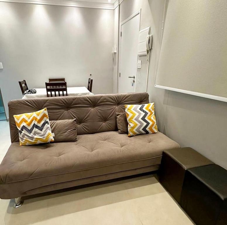 un sofá marrón con almohadas en una habitación en A tranquilidade está a seu alcance., en São Vicente