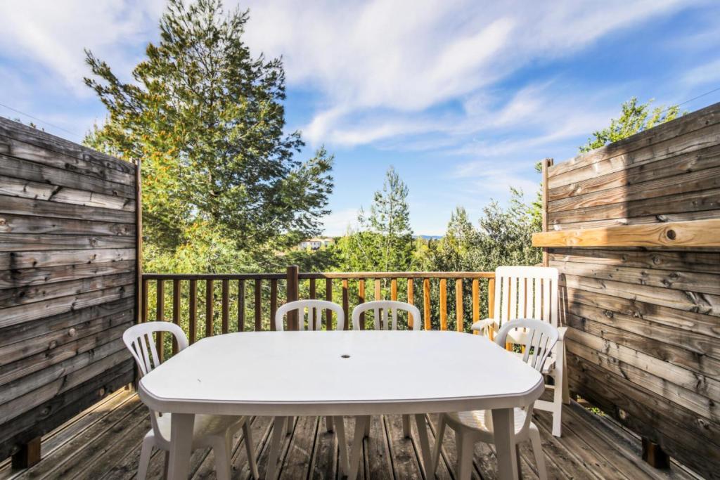 une table et des chaises blanches sur une terrasse en bois dans l'établissement Les maisons Le Rouret - maeva Home - Maison 2 pièces 5 personnes Sélection MAE-3554, à Grospierres