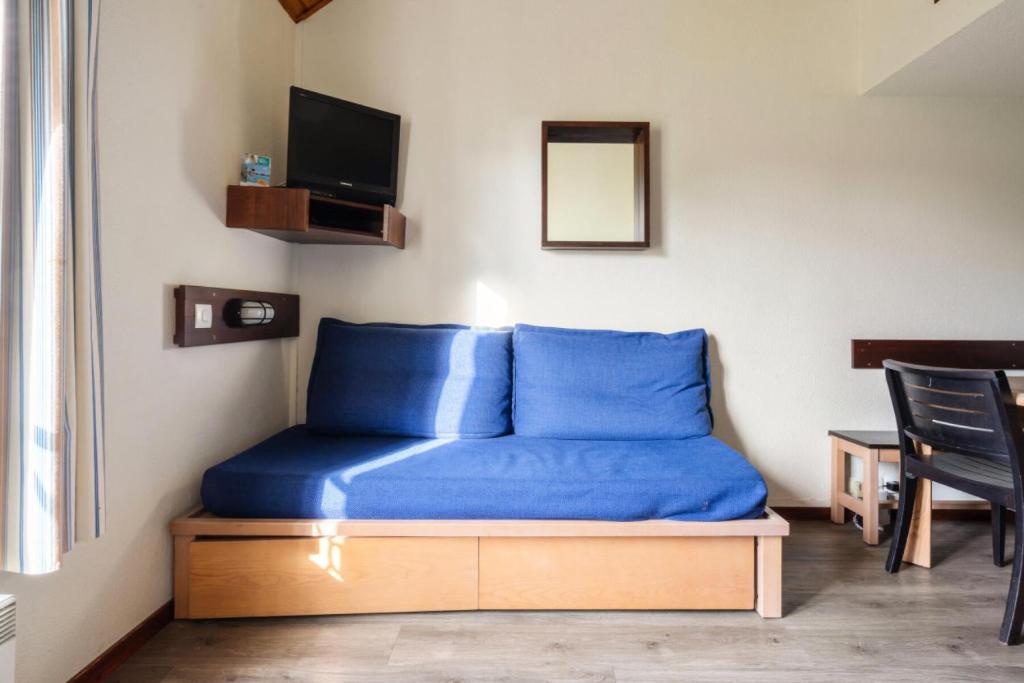 Cette chambre comprend un lit avec des draps bleus et une télévision. dans l'établissement Résidence Port du Crouesty - maeva Home - Appartement duplex 3 pièces 7 personnes Confort MAE-4806, à Arzon