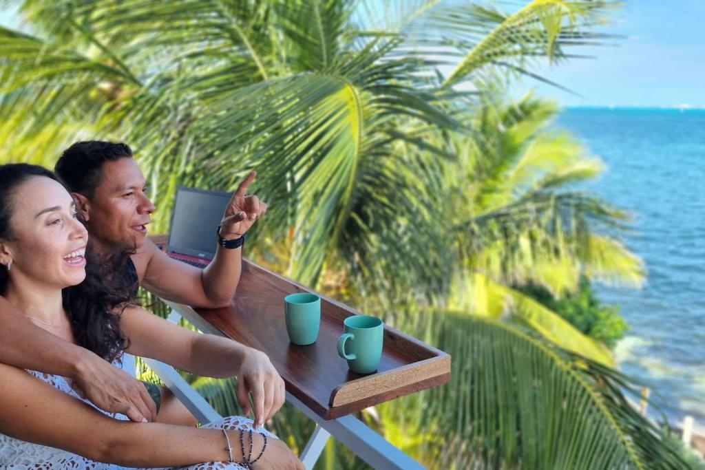 a man and a woman sitting at a table on the beach at On The Beach 2 - Seaside Sunrise Haven- Sea View in Cancún