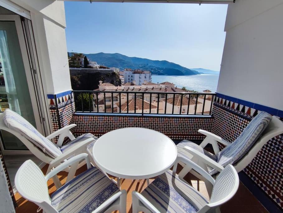 a table and chairs on a balcony with a view of the ocean at Primera línea de Playa in Almuñécar