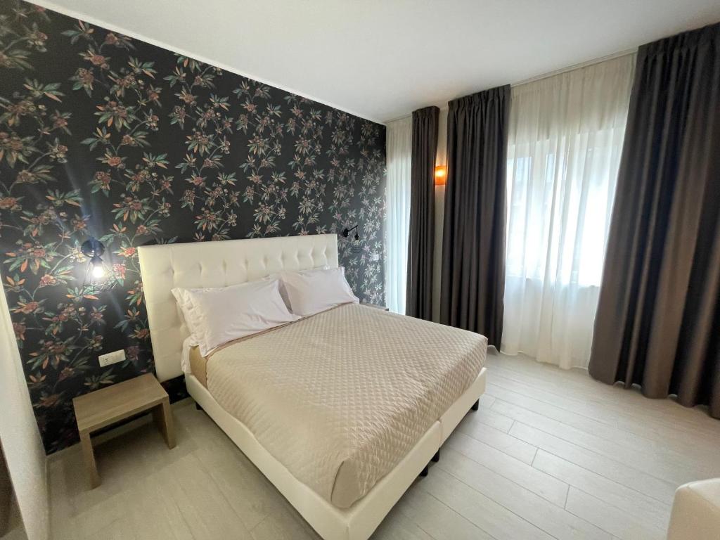 1 dormitorio con 1 cama y una pared con flores en Castrichella Boutique Hotel Rome Airport en Fiumicino