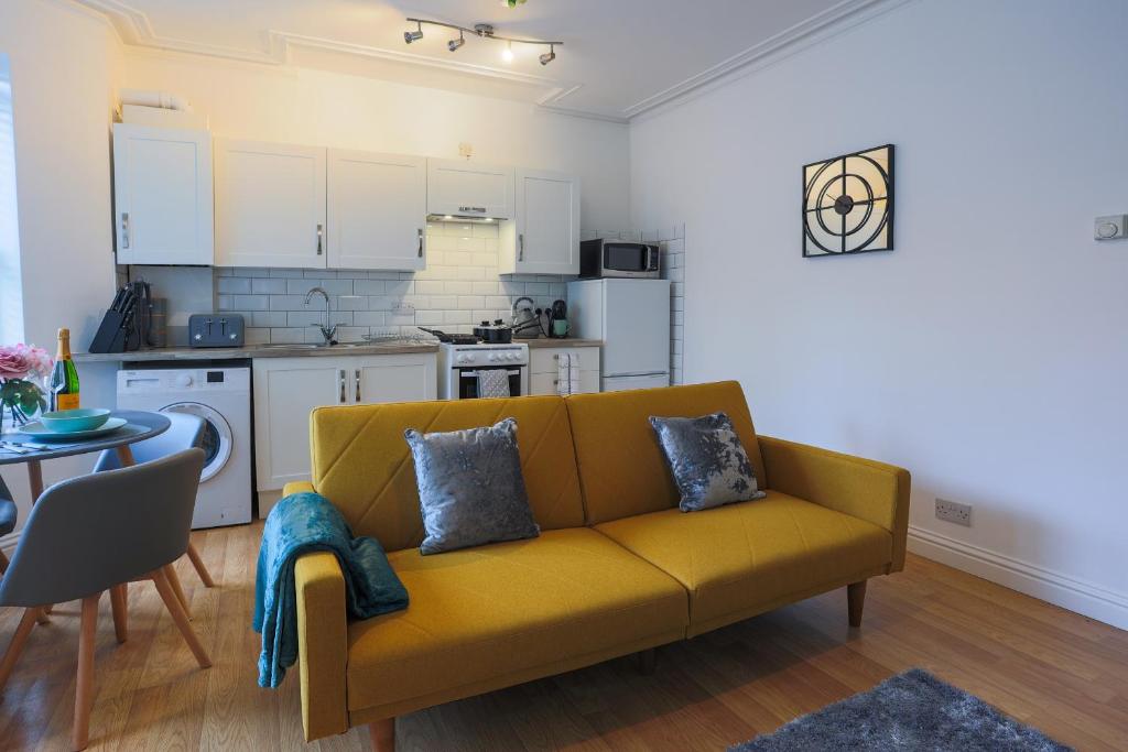 a living room with a yellow couch and a kitchen at The best flat on the street - Three minutes walk from the beach in Southend-on-Sea