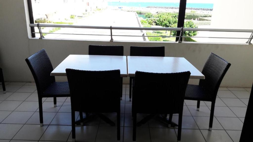 une table blanche et des chaises dans une pièce avec une fenêtre dans l'établissement Résidence Les Rivages de Rochelongue - maeva Home - Appartement 3 pièces 6 personnes Confort - Vue mer MAE-1585, au Cap d'Agde