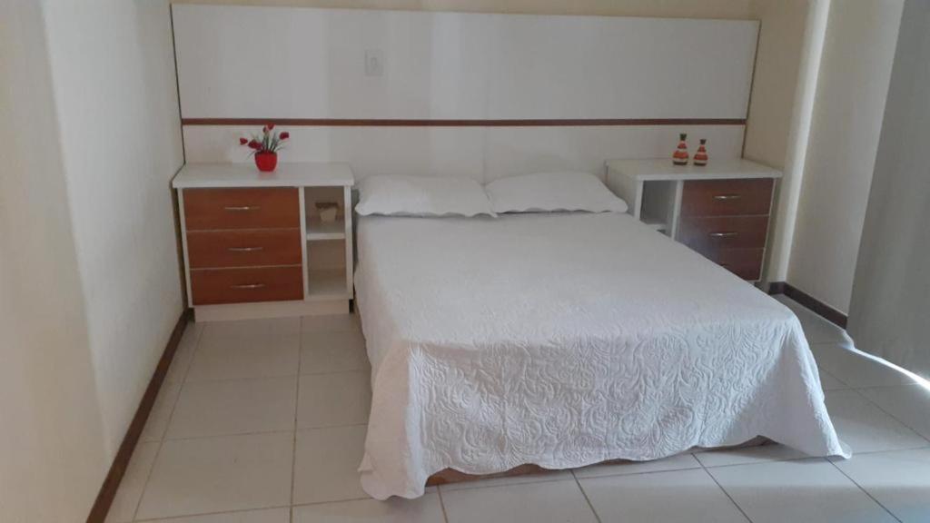 a bedroom with a white bed and two dressers at Férias em Família Apartamento Temporada in Cabo Frio