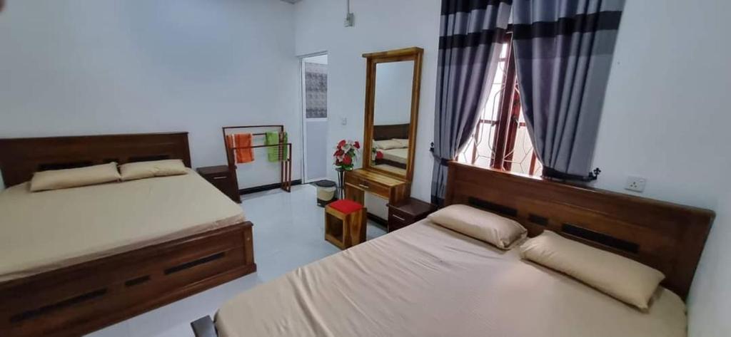 a bedroom with two beds and a mirror and a window at Nilaveli Guest House in Nilaveli