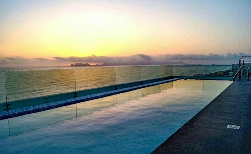 una piscina frente al océano al atardecer en Hermoso dpto con Vista al Mar, Piscina y Sauna, en Lima