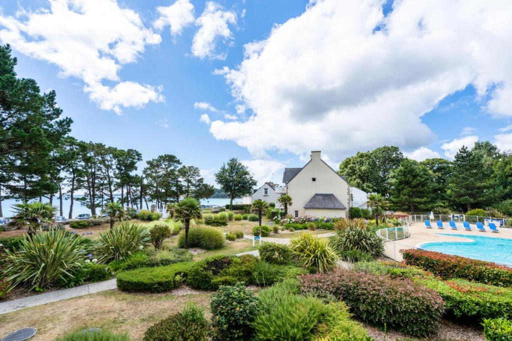 Elle offre une vue sur un jardin avec une piscine et une église. dans l'établissement Résidence Cap Azur - maeva Home - Appartement 3 Pièces 6 Personnes - Confort MAE-1051, à Fouesnant