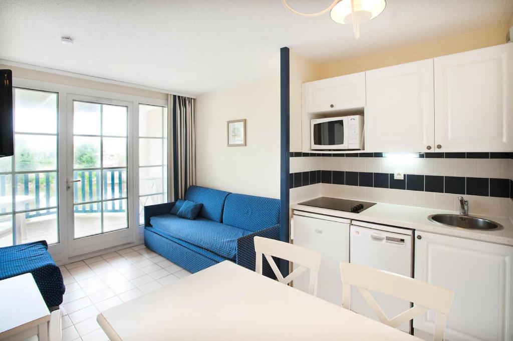 sala de estar con sofá azul y cocina en Résidence Port Bourgenay - maeva Home - Studio 5 Personnes Sélection 15, en Talmont