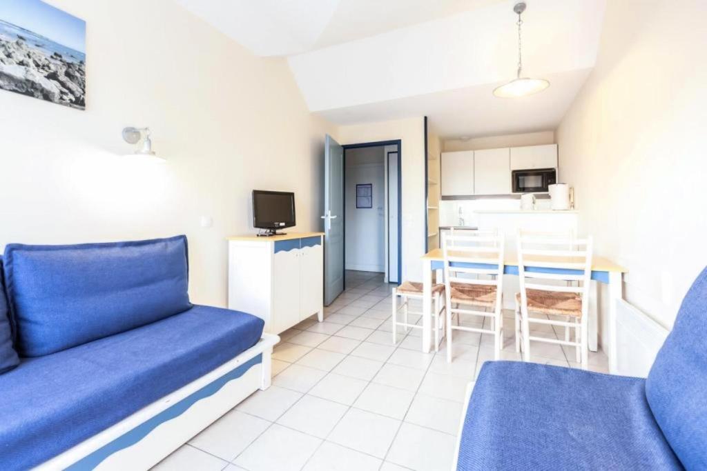un salon avec un canapé bleu et une cuisine dans l'établissement Résidence Port Bourgenay - maeva Home - Appartement 2 Pièces 5 Personnes - Sélection MAE-2073, à Talmont-Saint-Hilaire