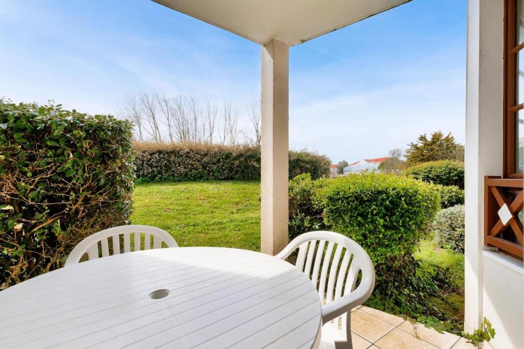 une table et des chaises blanches sur une terrasse couverte avec une fenêtre dans l'établissement Résidence Port Bourgenay - maeva Home - 2 Pièces 5 Personnes Sélection MAE-2081, à Talmont-Saint-Hilaire