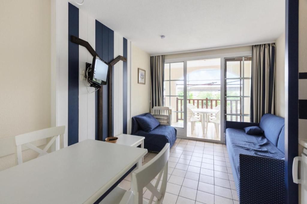 Il comprend un salon doté d'un mobilier bleu et d'un balcon. dans l'établissement Résidence Port Bourgenay - maeva Home - Appartement 2 pièces 5 personnes Selection MAE-3681, à Talmont-Saint-Hilaire